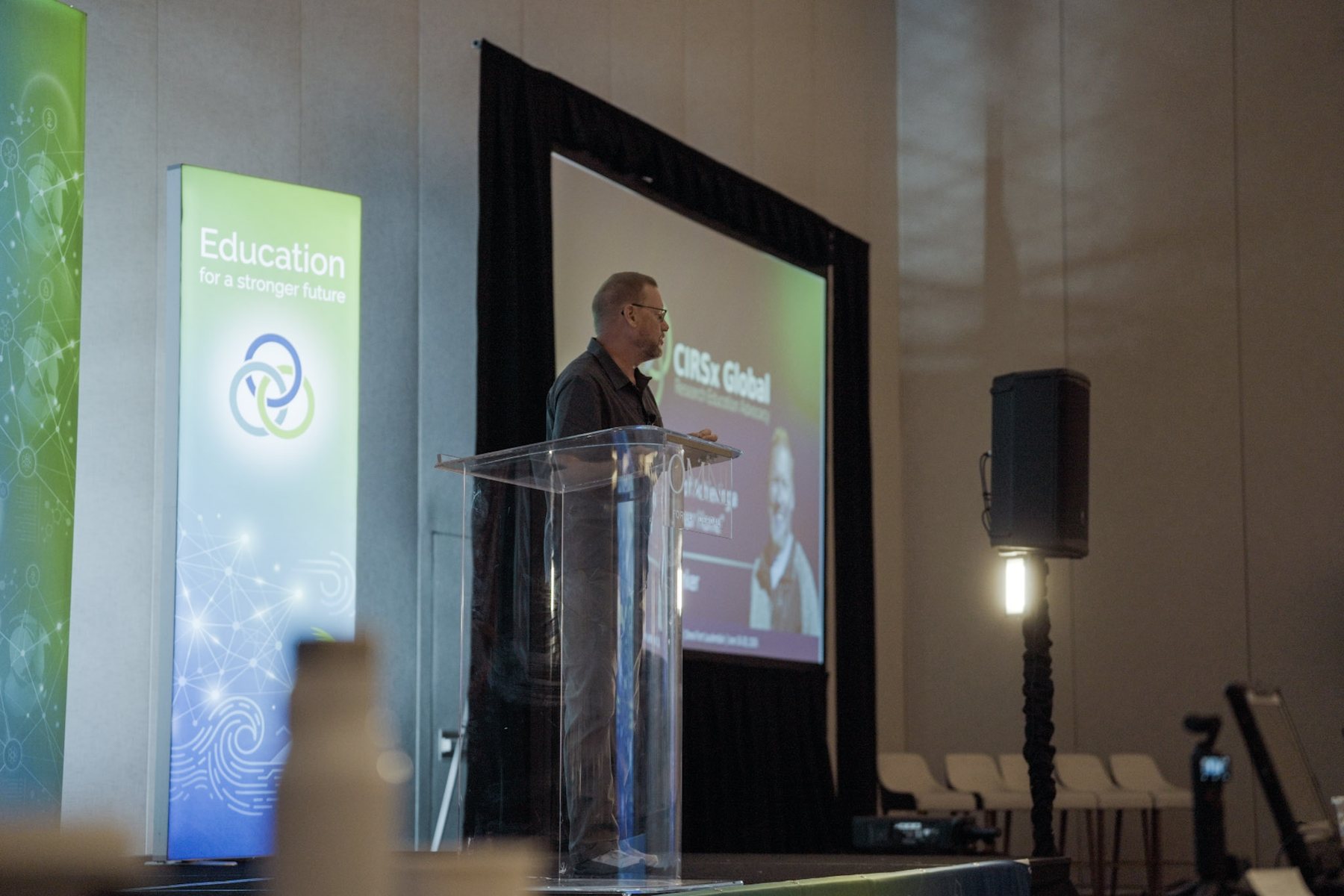 A speaker at a podium on stage at a conference