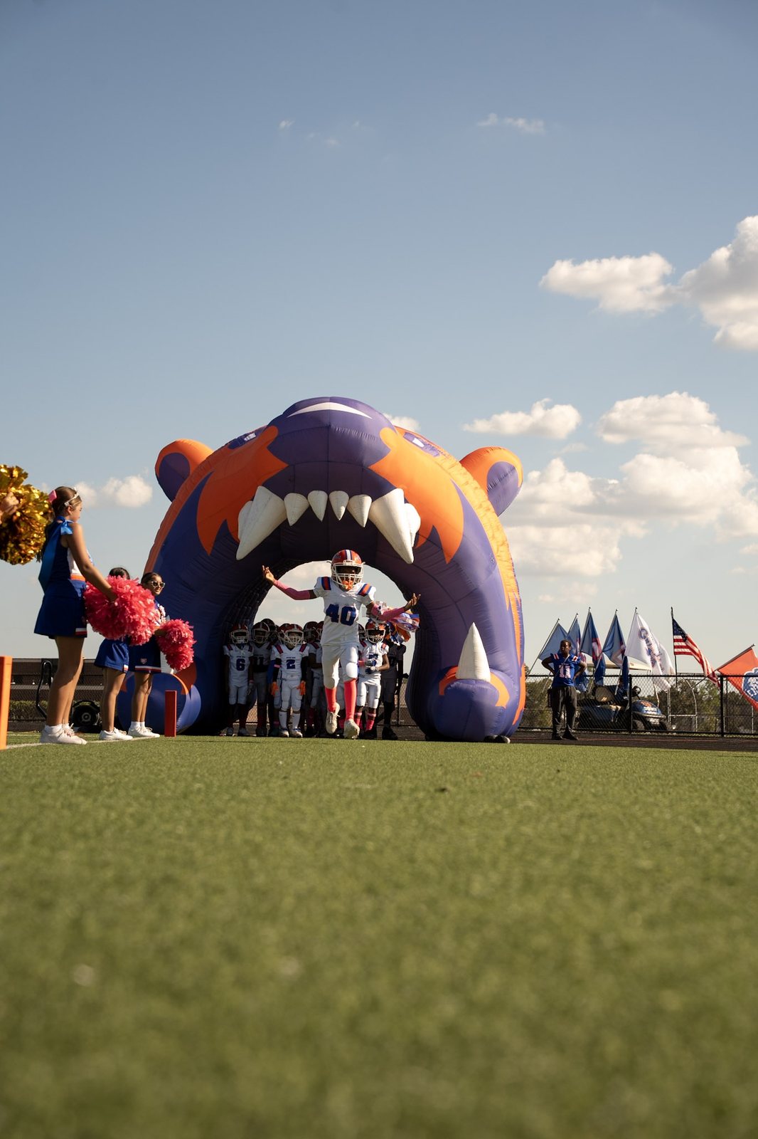 Cheerleaders and an inflatable tunnel as a player runs onto the field