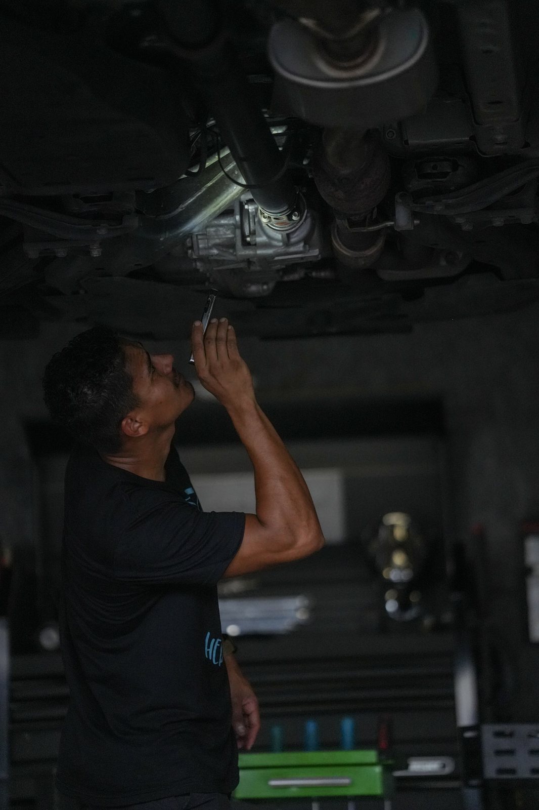 A mechanic working overhead under a vehicle in low light