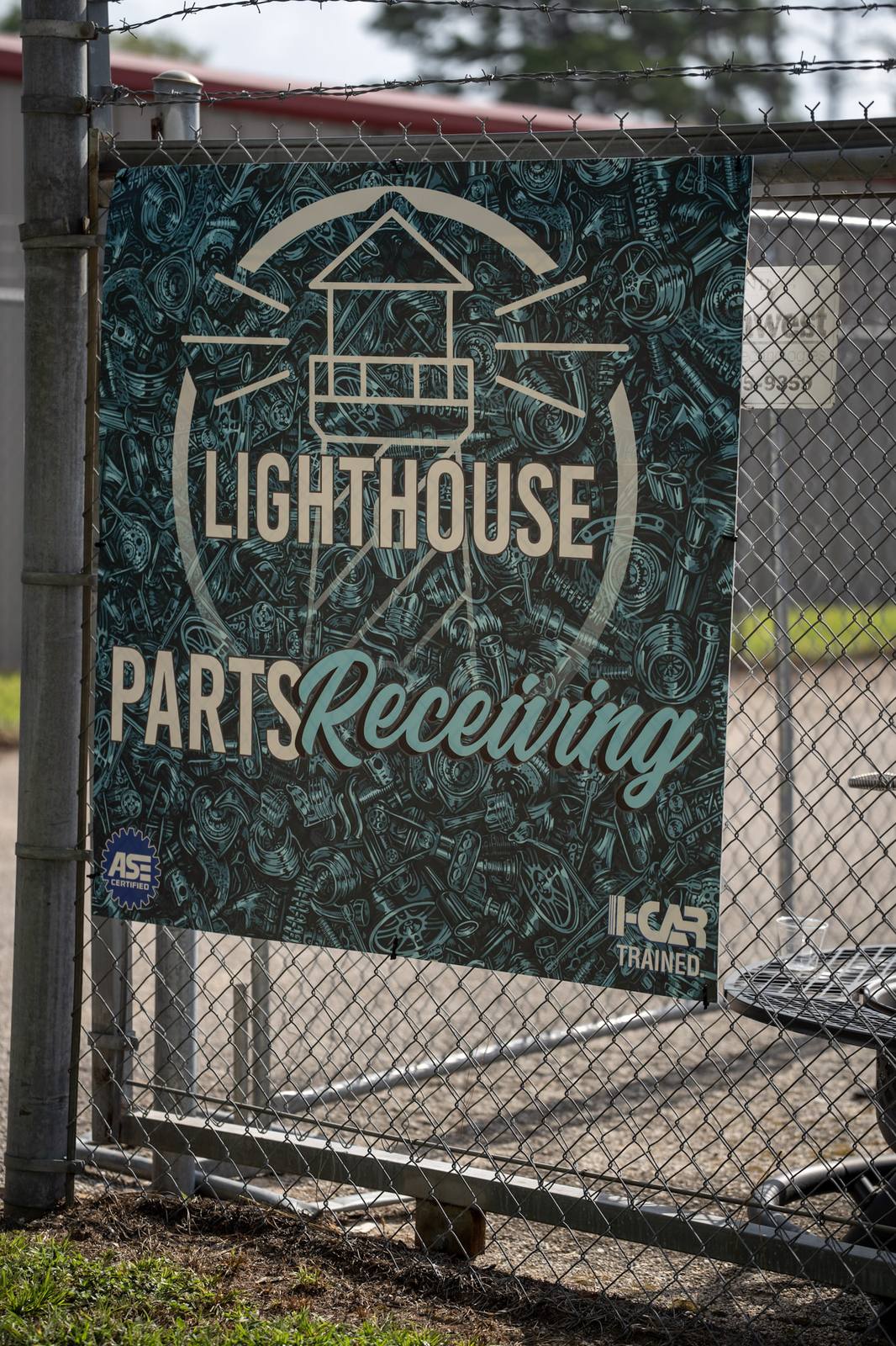 A parts receiving sign hanging on a fence outside the shop
